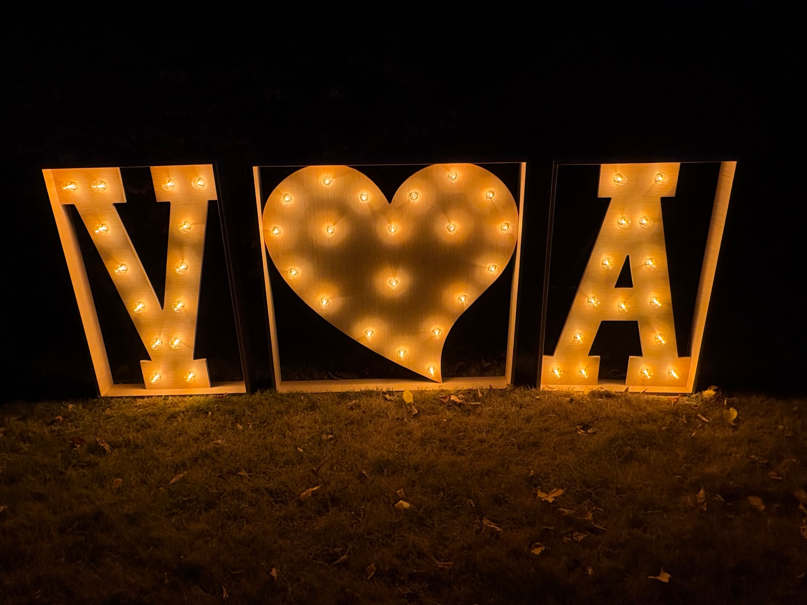 Lichtletters V hart A op het gras tijdens een avondfeest